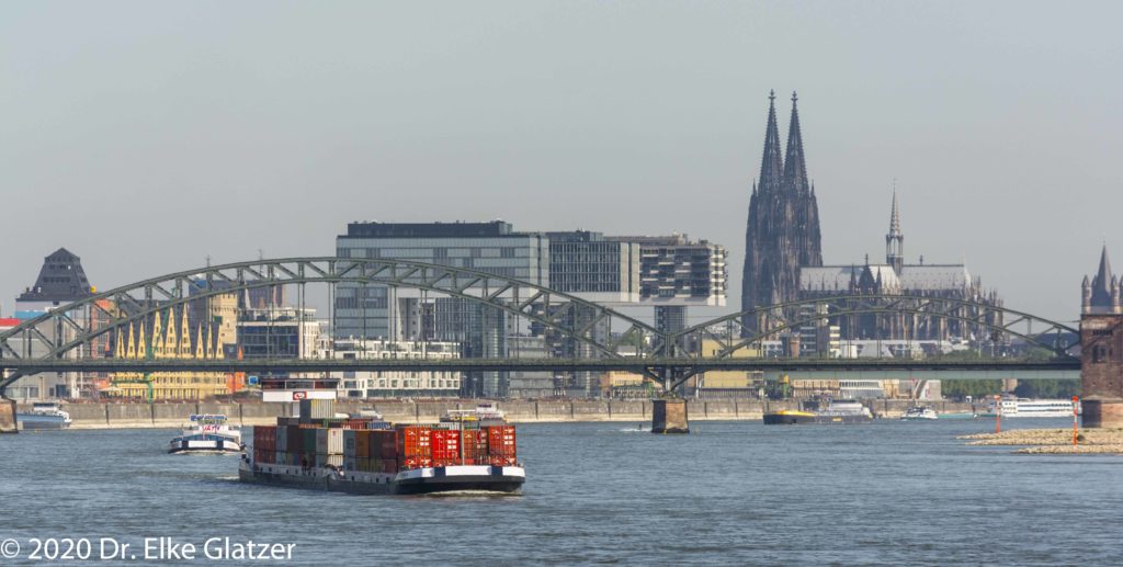 Kölner Panorama mit Südbrücke, Kranhäusern und Dom; davor auf dem Rhein ein Containerschiff